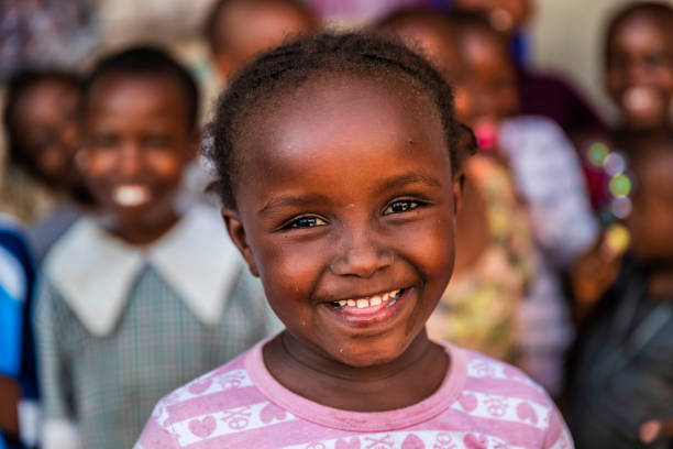 Group of colorful dressed, happy African children, orphanage in Kenya. There is no light and electricity inside the classroom. Around 20-30 orphans live in this orphanage which is located near Nairobi.